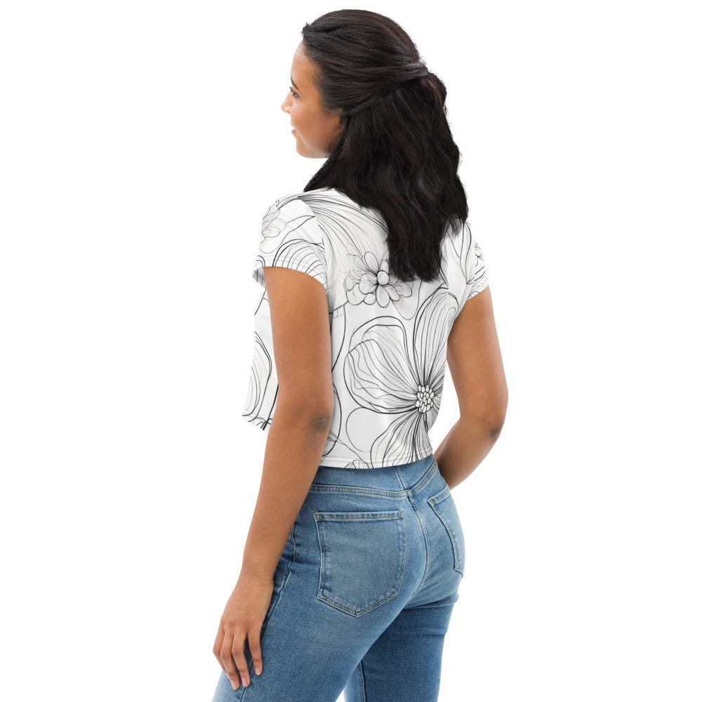 A white all-over print crop tee featuring a striking black floral pattern with outlined flowers, worn by a model paired with blue jeans—perfect for chic casual styling