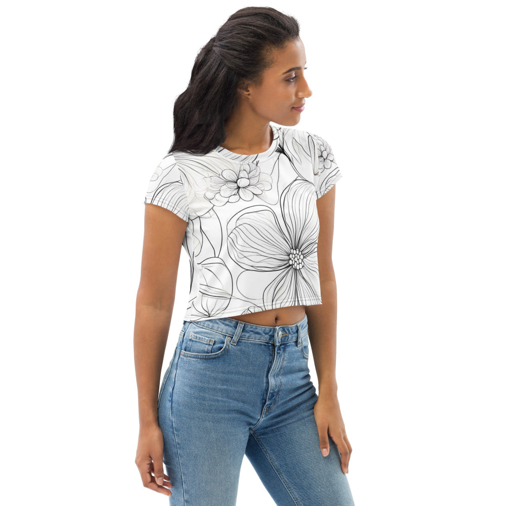 A white all-over print crop top featuring a bold black floral pattern with large flowers and leaves, worn by a model paired with blue jeans—perfect for chic casual styling