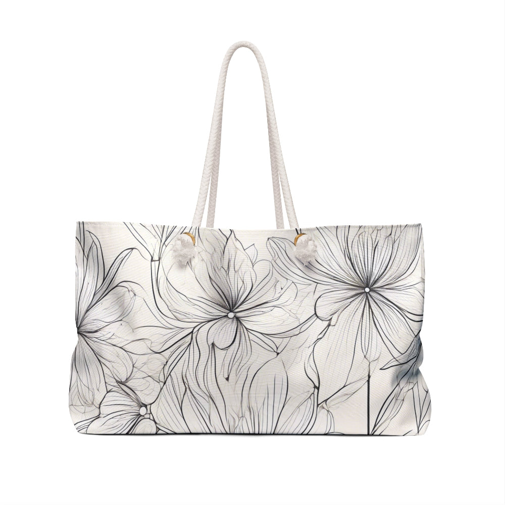 A white tote bag featuring an intricate black floral line drawing with outlined flowers, complemented by two white handles—perfect for stylish everyday use