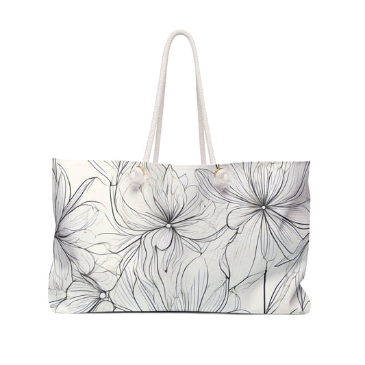 A white tote bag featuring a delicate black floral line drawing with large outlined flowers, equipped with white handles—perfect for stylish everyday use